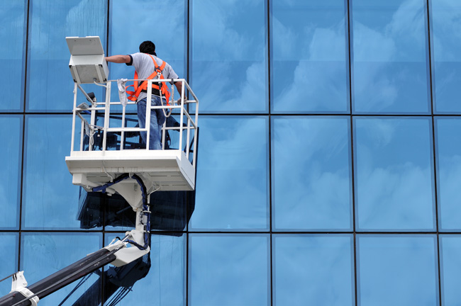 Worker on a crane cleaning windows of a building