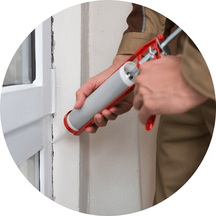 man working sealing the cracks of a window